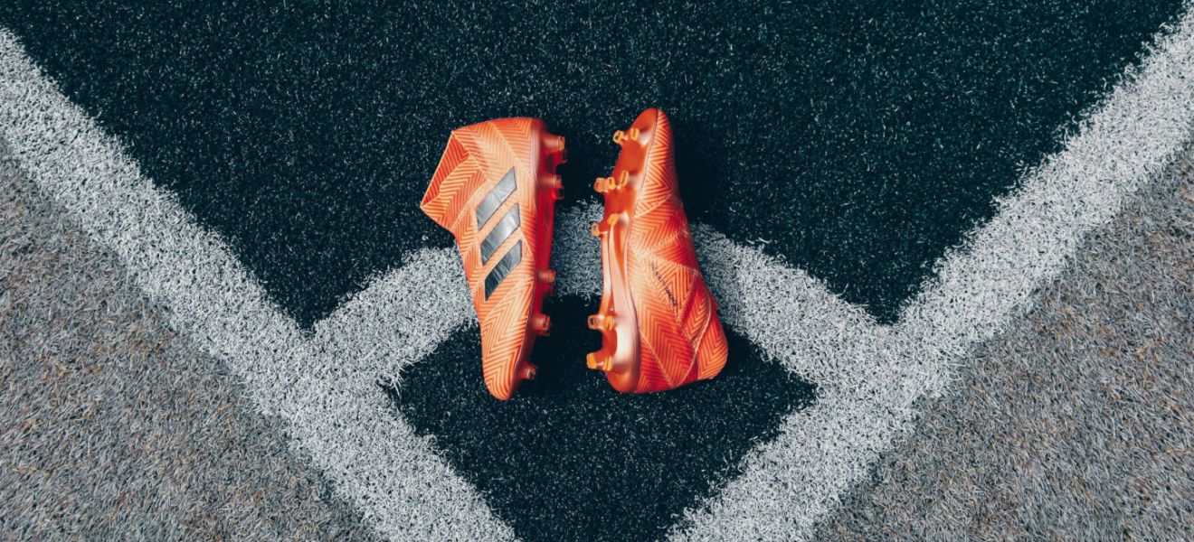 Orange football boots laying on corner of football pitch